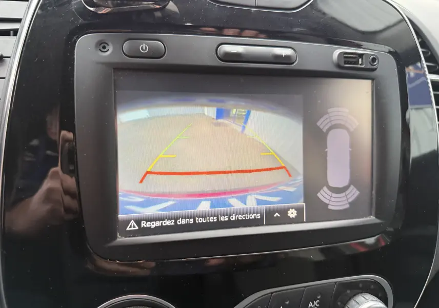 Écran central de la Renault Captur rouge 2017 montrant la caméra de recul avec guidage et capteurs de proximité.