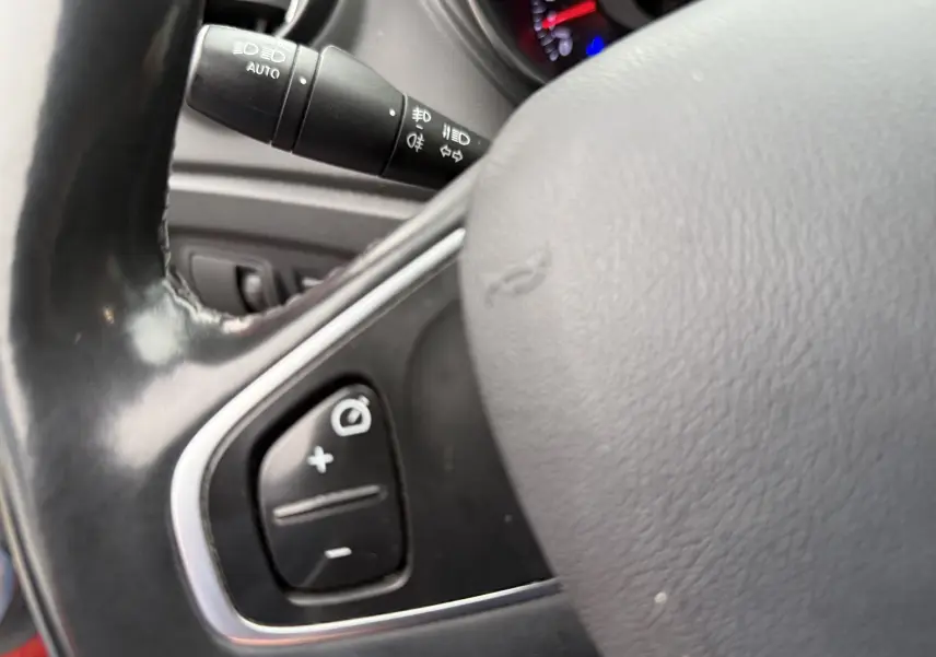 Gros plan sur le volant noir du Renault Captur rouge 2017, avec commandes intégrées visibles côté gauche.