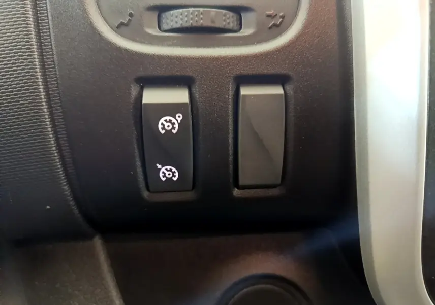 Gros plan sur les boutons de commande du régulateur de vitesse dans l’habitacle du Renault Trafic Fourgon blanc 2021.