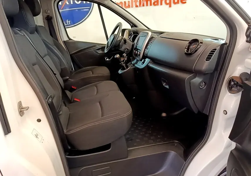 Intérieur côté conducteur du Renault Trafic blanc, montrant les sièges avant, tableau de bord et volant réglable.