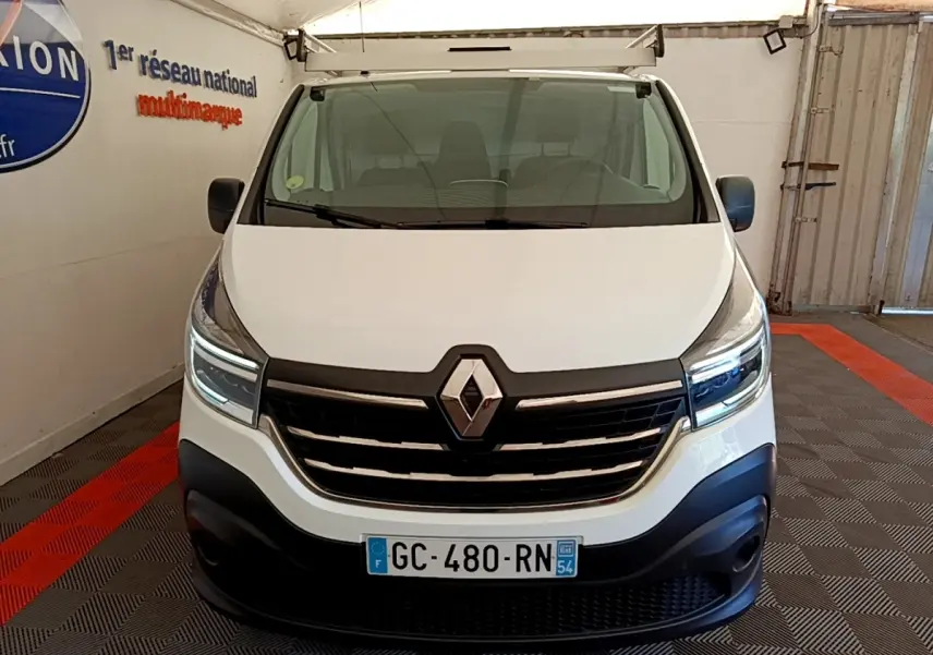 Vue frontale d’un Renault Trafic Fourgon blanc 2021 avec calandre noire et feux LED allumés dans un garage.