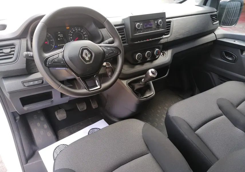 Vue intérieure côté conducteur du Renault Trafic Fourgon 2024, tableau de bord noir avec volant multifonction et boîte manuelle.