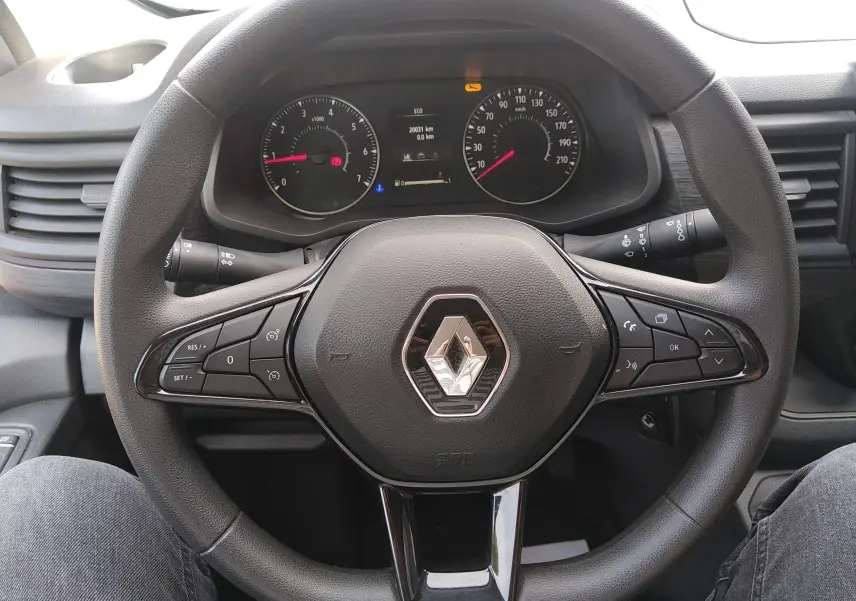 Vue rapprochée du volant noir du Renault Trafic Fourgon 2024 avec commandes intégrées et tableau de bord visible.
