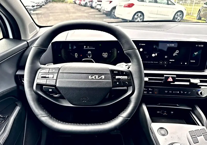 Vue intérieure centrée sur le volant noir multifonction du Kia Sportage 1.6 hybride 2026 avec tableau de bord digital et écran tactile.