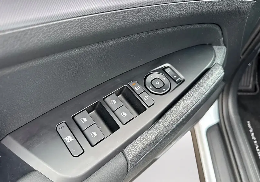 Vue rapprochée du panneau de commandes des vitres côté gauche intérieur d’un KIA Sportage blanc avec boutons noirs.