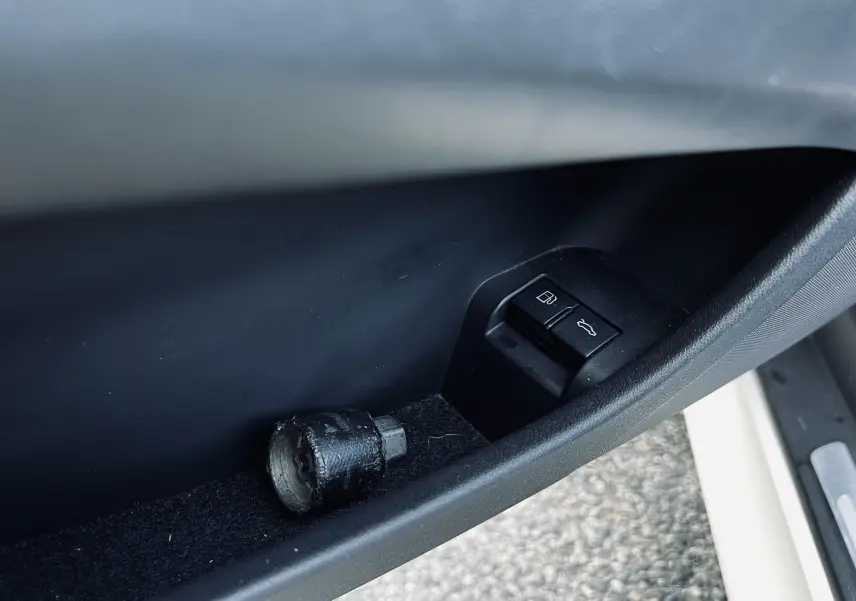 Gros plan sur la commande d'ouverture du coffre et du réservoir côté conducteur d'un Audi TT RS Roadster blanc.