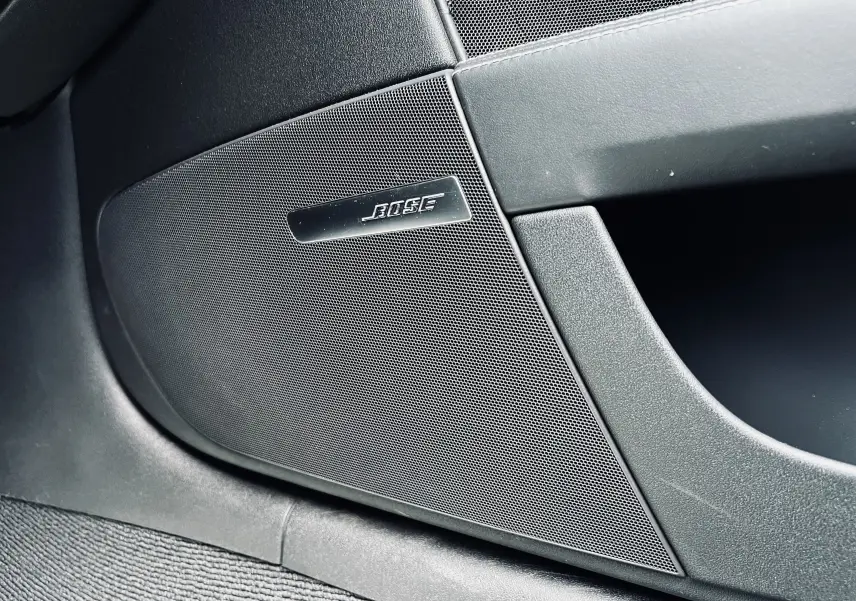 Gros plan sur l'enceinte Bose intégrée à la porte intérieure noire de l'Audi TT RS Roadster blanc.