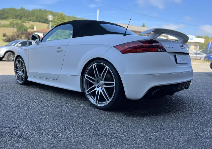 Audi TT RS Roadster blanc vue 3/4 arrière côté gauche avec capote noire et aileron arrière distinctif