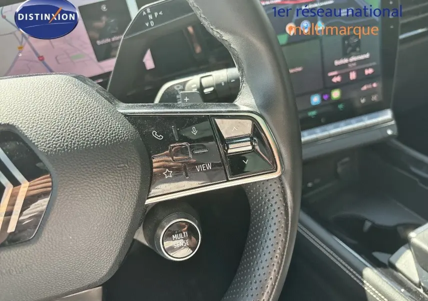 Gros plan sur le volant noir perforé du Renault Austral 2024 avec commandes intégrées et bouton Multi Sense visible.