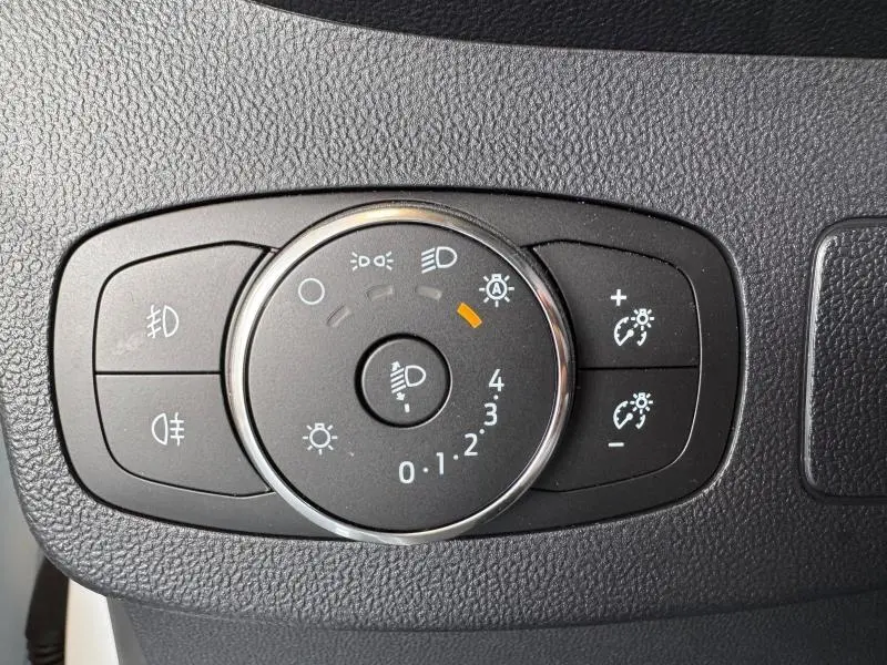 Gros plan sur le bouton de réglage des phares du Ford Puma blanc Glacier, avec commandes d'éclairage et antibrouillard.