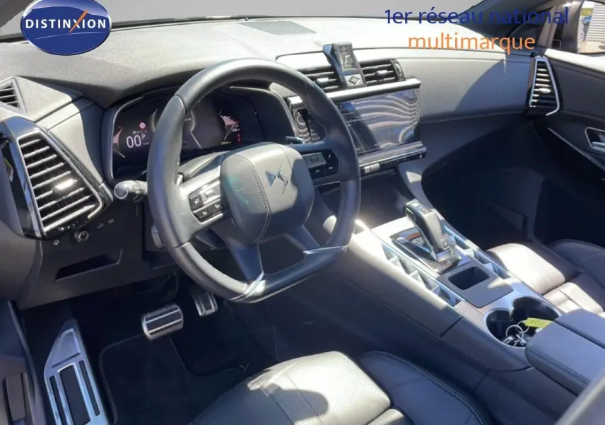 Vue intérieure de face du poste de conduite du DS7 2024 noir métal, avec volant cuir et console centrale moderne.