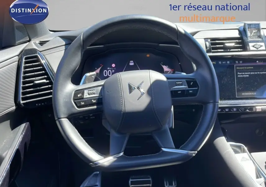 Vue rapprochée du volant cuir noir du DS7 2024 avec commandes intégrées et tableau de bord numérique lumineux.