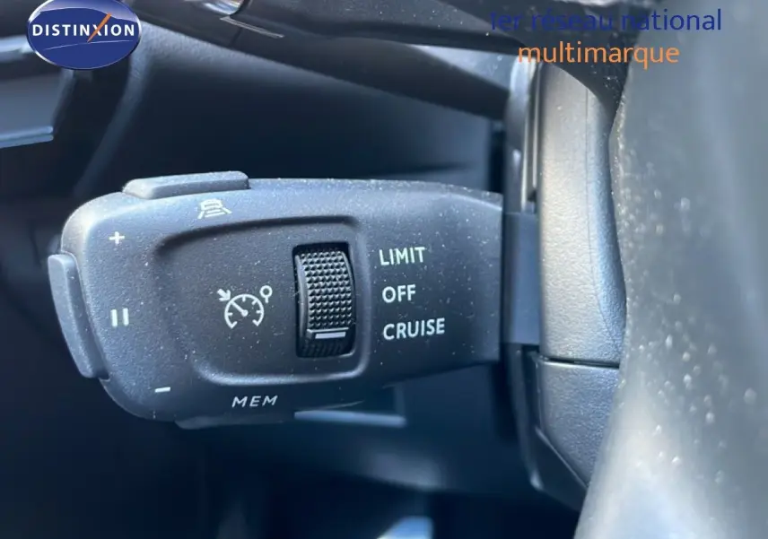 Gros plan sur la commande de régulateur de vitesse à gauche du volant dans un DS7 noir métal 2024.