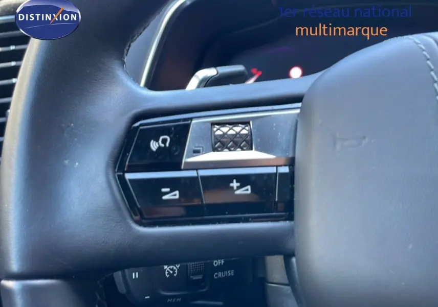 Gros plan sur les commandes gauche du volant en cuir noir du DS7 2024, avec boutons de volume et fonction mains libres.