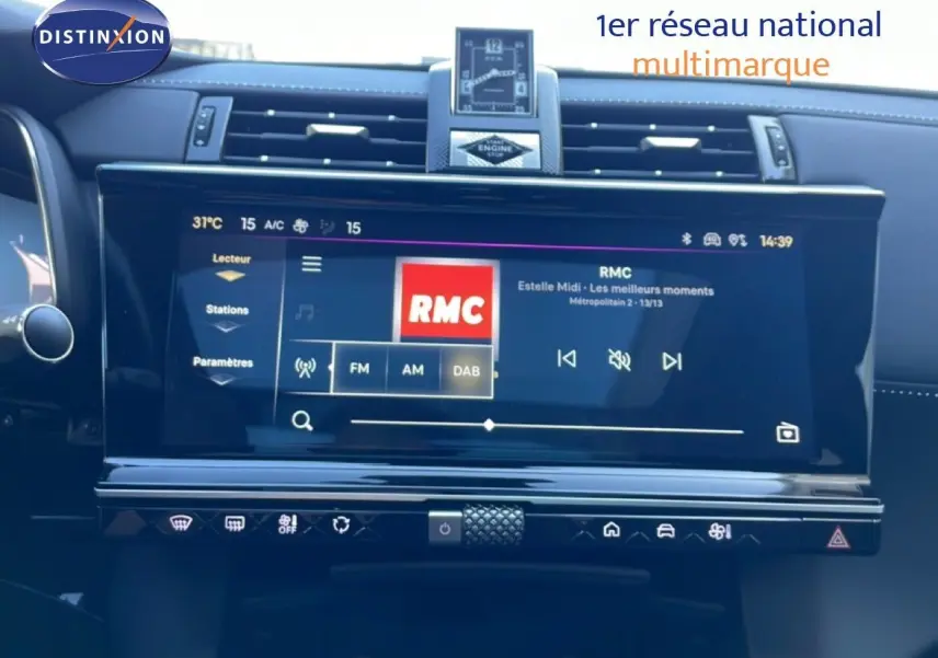 Vue rapprochée de l’écran tactile central du tableau de bord du DS7 noir métal 2024, affichant la radio RMC.