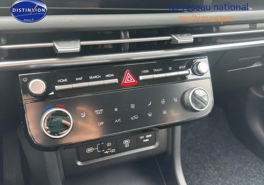 Tableau de bord noir du Hyundai Tucson 2025 avec commandes tactiles et boutons rotatifs de climatisation et multimédia.