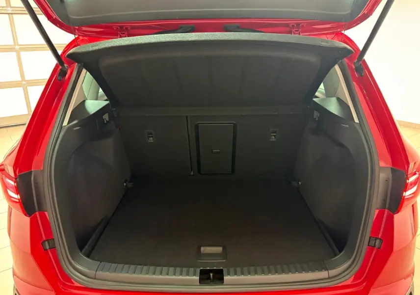 Coffre ouvert vu de l'arrière d'un SEAT Ateca 2024 Rouge Velvet avec plancher à double fond visible.
