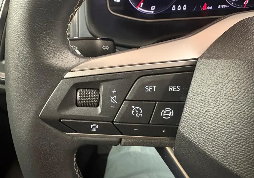 Vue rapprochée du volant côté gauche du SEAT Ateca 2024 Rouge Velvet, montrant les commandes de régulateur de vitesse.