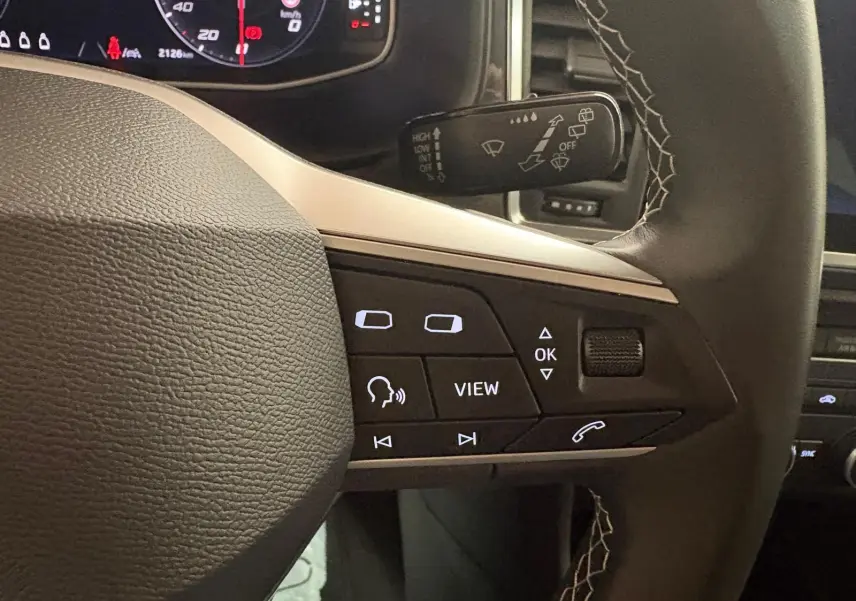 Gros plan sur les commandes au volant du SEAT Ateca 2024, mettant en valeur les boutons multifonctions et le cuir noir.