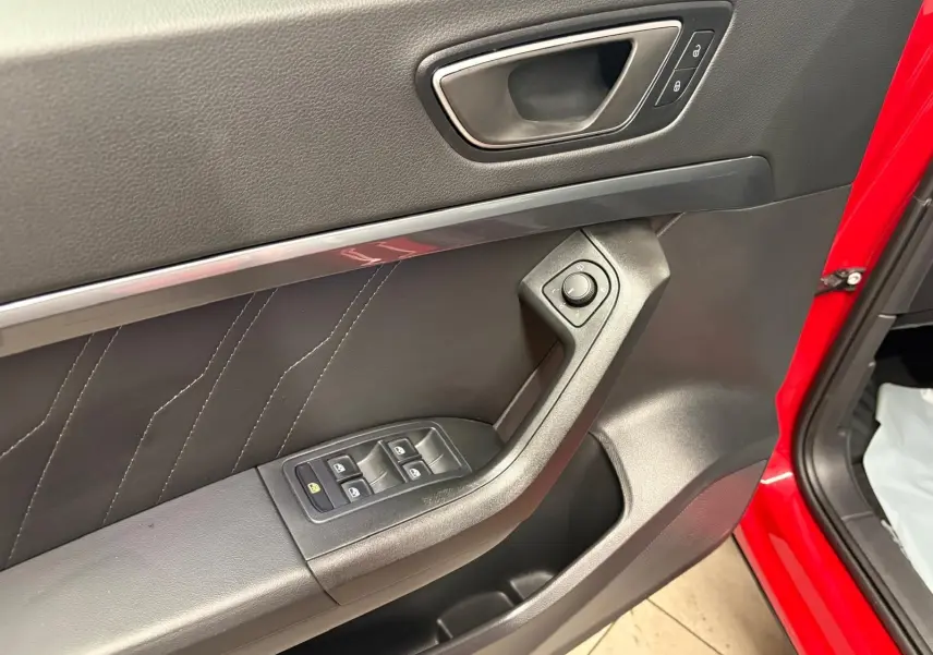 Gros plan sur la porte avant gauche rouge Velvet du SEAT Ateca 2024 avec commandes des vitres et réglage des rétroviseurs.