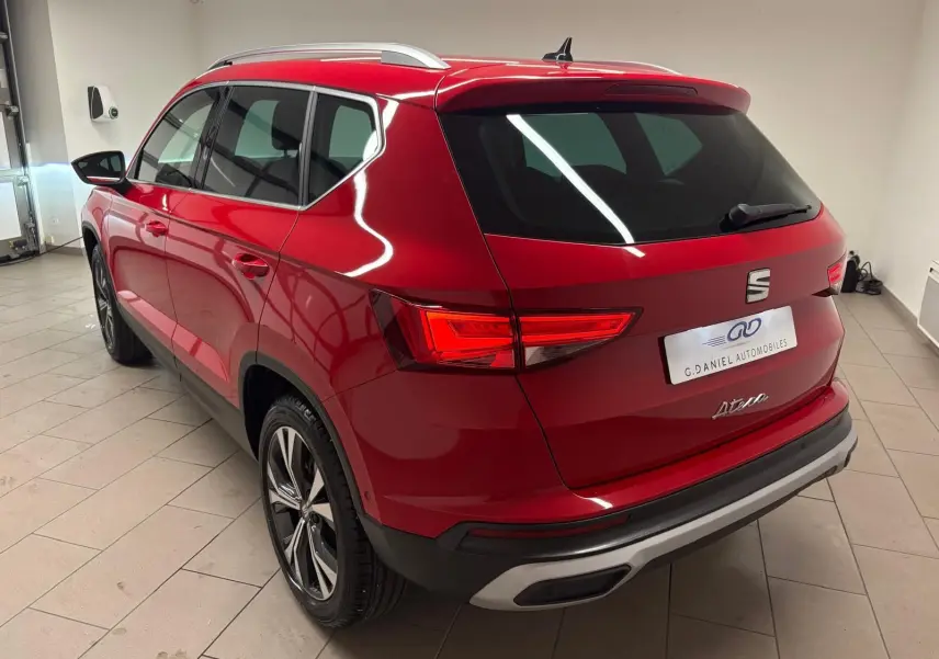 Vue 3/4 arrière droite du SEAT Ateca Rouge Velvet 2024 avec feux allumés et jantes alliage distinctives.