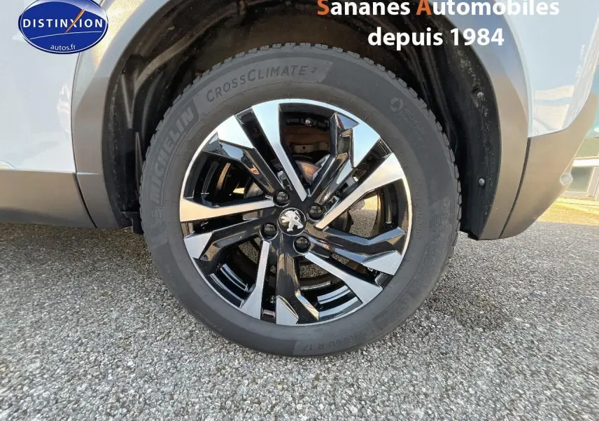 Gros plan sur la jante alliage 17'' bi-ton noir et argent du côté arrière droit d'un Peugeot 2008 blanc.