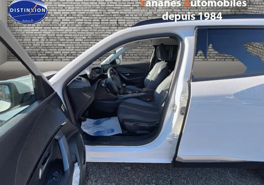 Peugeot 2008 blanc vue côté gauche avec porte avant ouverte et intérieur noir visible.