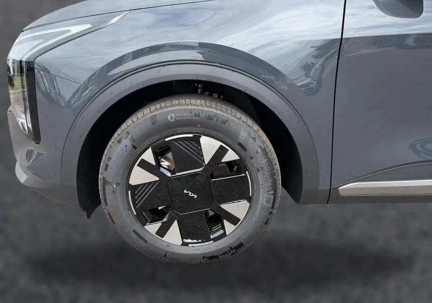 Gros plan sur la roue avant gauche d’un KIA SPORTAGE gris eclipse, mettant en valeur la jante alu 17 pouces au design moderne.