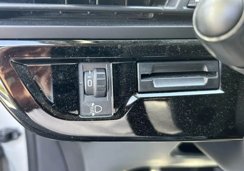 Gros plan sur le réglage de hauteur des phares dans l'habitacle noir brillant du Citroën Grand C4 Spacetourer beige clair 2018.
