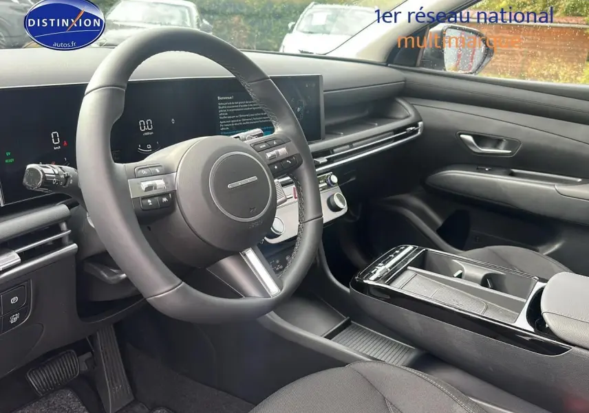 Intérieur du Hyundai Tucson 2025 hybride, vue côté conducteur, tableau de bord moderne avec écran tactile et volant cuir noir.