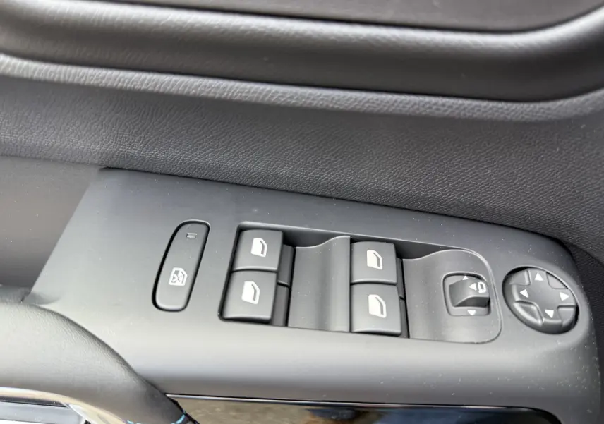 Gros plan sur les commandes de lève-vitres et réglages des rétroviseurs côté conducteur, finition cuir noir.
