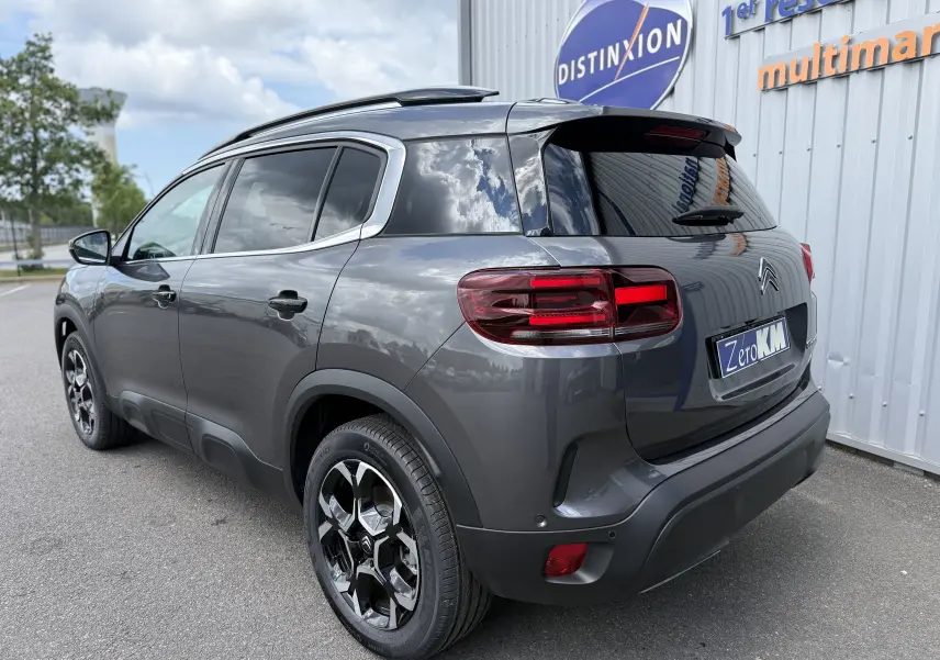 Vue 3/4 arrière droite d'un Citroën C5 Aircross gris platinium métallisé avec jantes bi-ton et vitres teintées.
