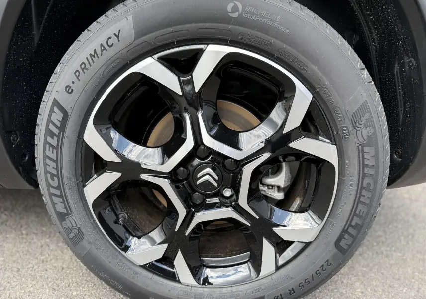 Gros plan sur la jante noire et argentée avec logo Citroën, montée sur pneu Michelin e.PRIMACY, côté droit du C5 Aircross gris.