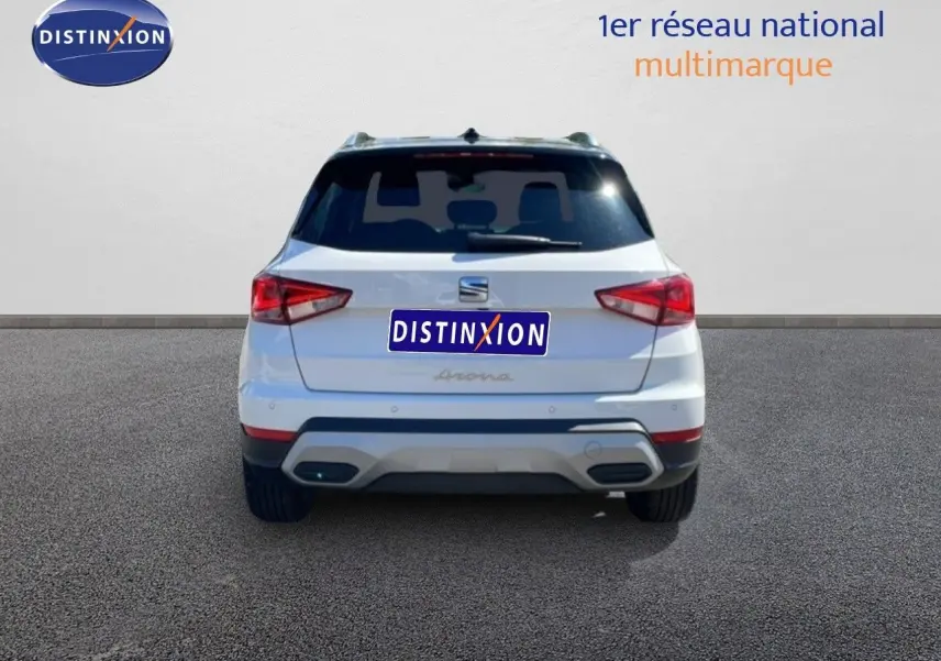 Vue arrière d'un SEAT Arona blanc avec toit noir, montrant les feux arrière et le logo distinctif au centre.