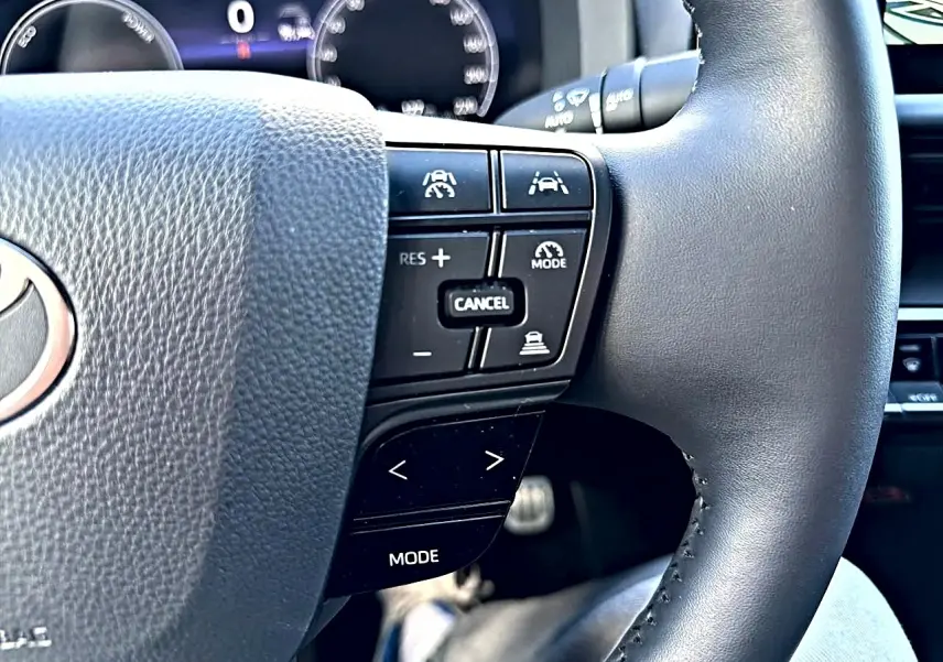 Gros plan sur le volant multifonction noir du Toyota C-HR gris, avec commandes de régulateur et assistance visibles.