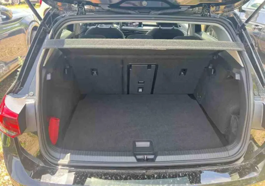 Coffre ouvert vue arrière d'une Volkswagen Golf VIII 1.5 TSI noire Deep Black, intérieur spacieux et propre.