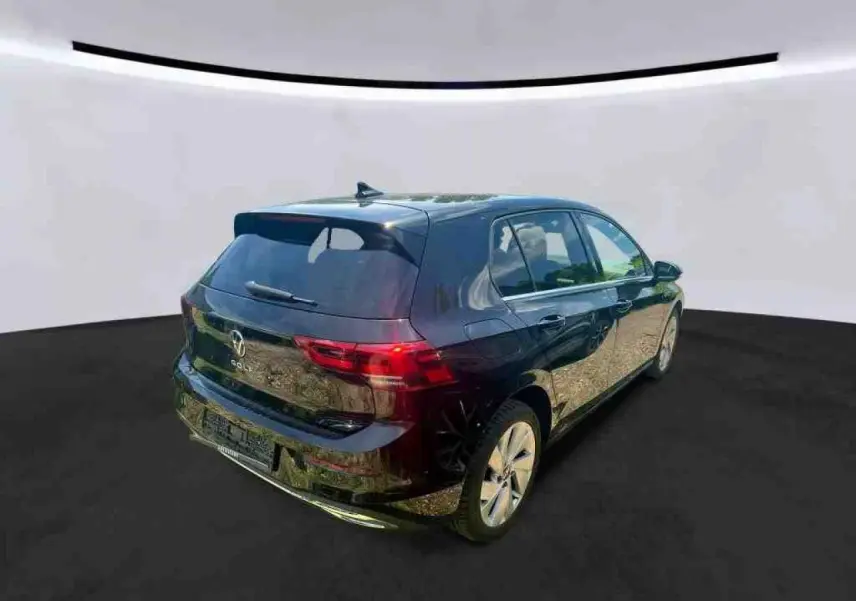 Vue 3/4 arrière droite d'une Volkswagen Golf VIII Deep Black avec vitres arrière surteintées et jantes alliage 17 pouces.