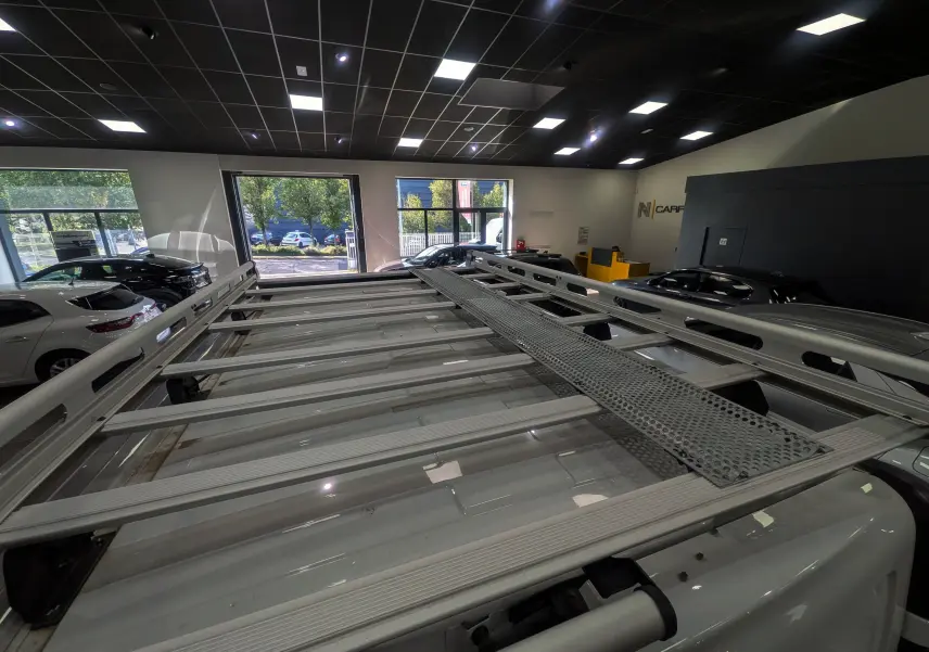 Vue plongeante sur la galerie de toit en aluminium du Renault Trafic Cabine Approfondie blanc minéral dans un showroom.