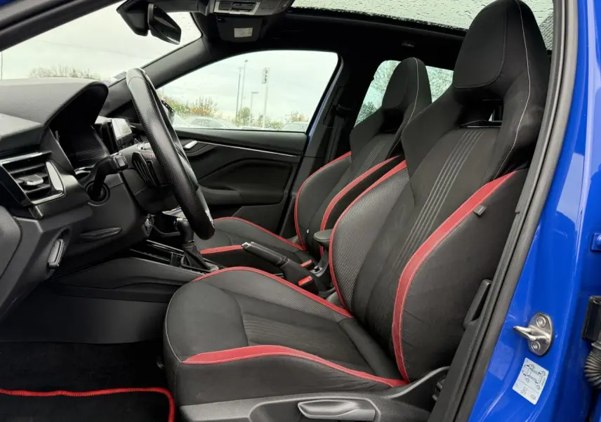 Vue intérieure côté conducteur du Skoda Kamiq bleu Energy 2021, sièges sport noirs avec surpiqûres rouges et volant cuir.