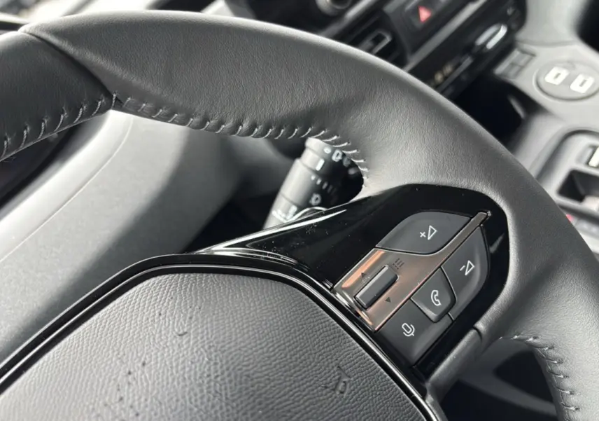 Gros plan sur le volant cuir multifonctions noir du Peugeot Rifter, avec commandes audio et téléphone intégrées.