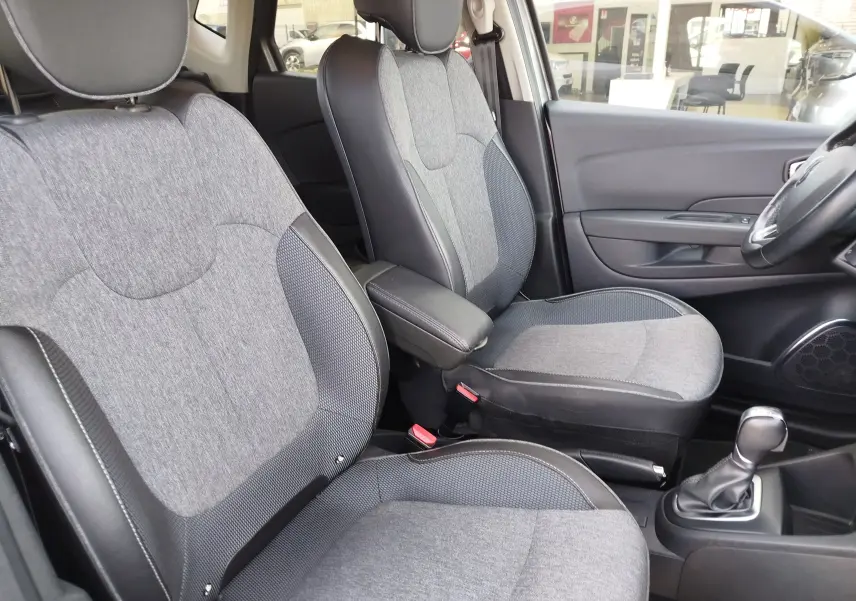 Vue intérieure côté droit des sièges avant gris clair et foncé du Renault Captur avec accoudoir central et levier de vitesses automatique.