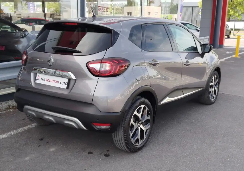 Vue 3/4 arrière droite d'un Renault Captur gris Cassiopée avec jantes bi-ton et feux arrière LED distinctifs.