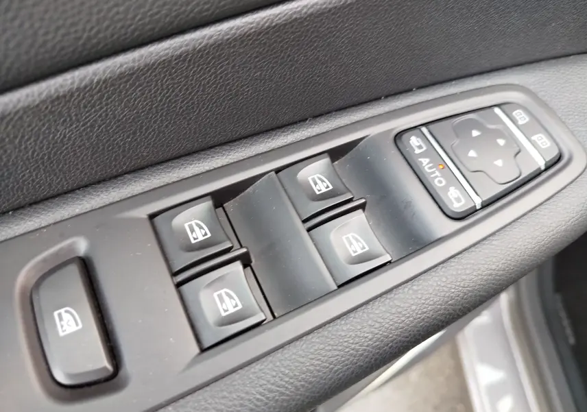 Gros plan sur les commandes de lève-vitres et réglages des rétroviseurs côté conducteur du Renault Captur Gris Cassiopée.