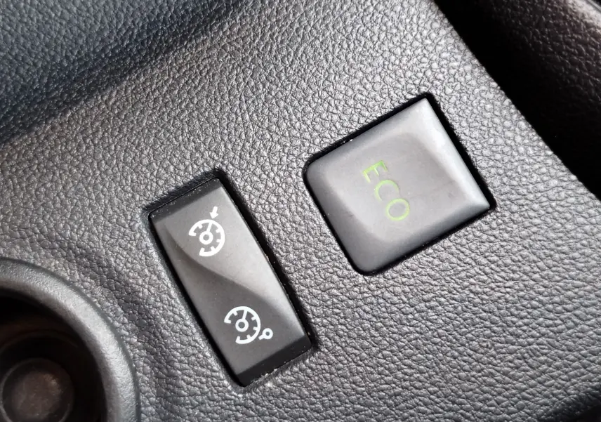 Gros plan sur les boutons de commande du régulateur de vitesse et mode ECO dans l'habitacle du Renault Captur gris Cassiopée.