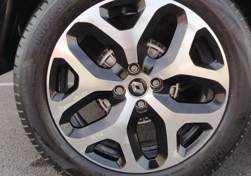 Gros plan sur la jante alliage bicolore noire et argent avec logo Renault au centre du Renault Captur Gris Cassiopée.