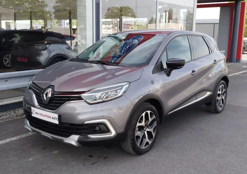 Renault Captur Gris Cassiopée en 3/4 avant droit, avec jantes bi-ton et signature lumineuse LED visible.