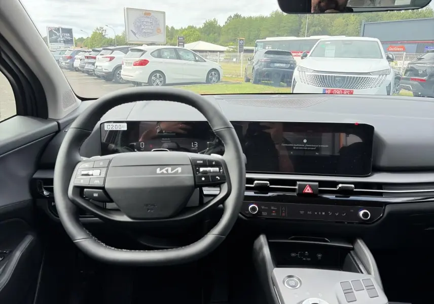 Vue intérieure centrée sur le volant cuir multifonction et tableau de bord numérique du Kia Sportage 1.6 hybride gris eclipse.