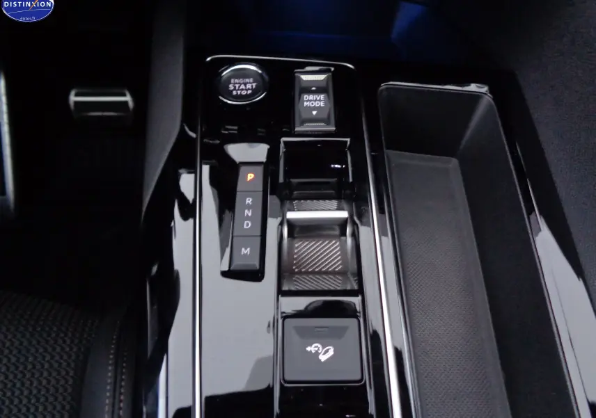 Gros plan sur la console centrale noire brillante du Peugeot 3008 2023 avec levier de vitesses et bouton start/stop.