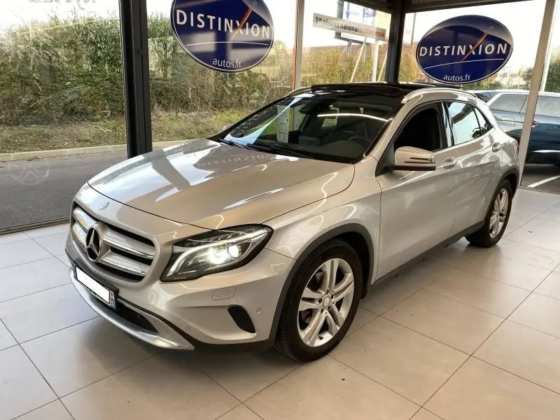 Mercedes GLA 200 Sensation gris montagne en 3/4 avant droit, phares LED allumés dans un showroom lumineux.