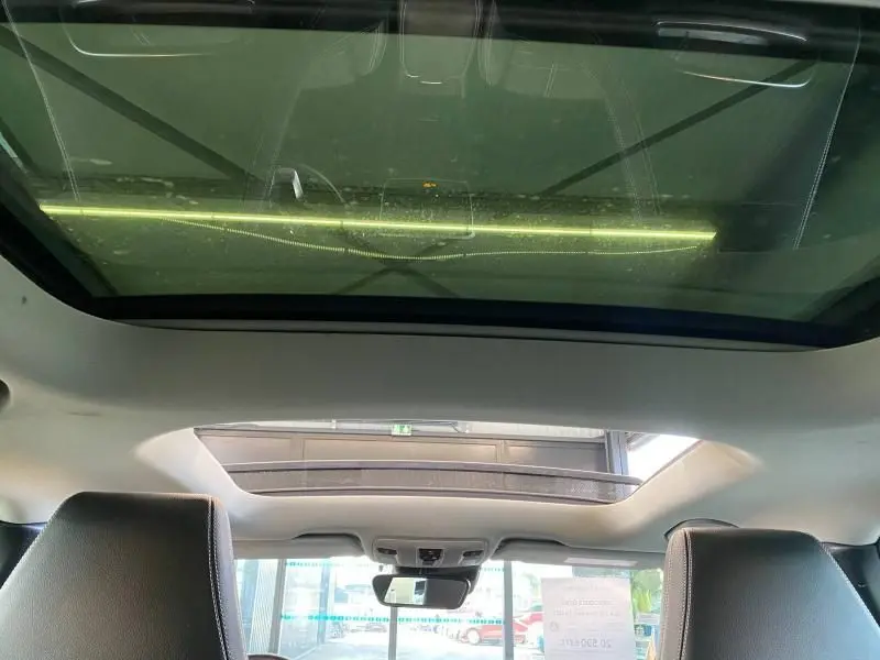 Vue intérieure du toit ouvrant panoramique du Mercedes GLA 200 Sensation gris montagne, avec sièges avant en cuir visibles.